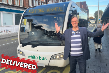 Jonathan Lord MP Standing Outside a White Bus